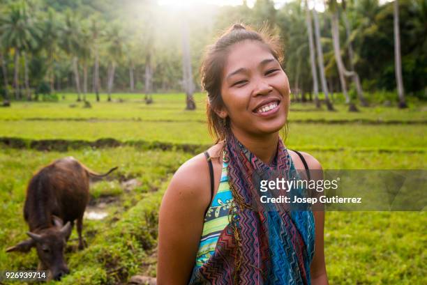 young smiley asian woman looking at camera in a rural scene - filipino stockfoto's en -beelden