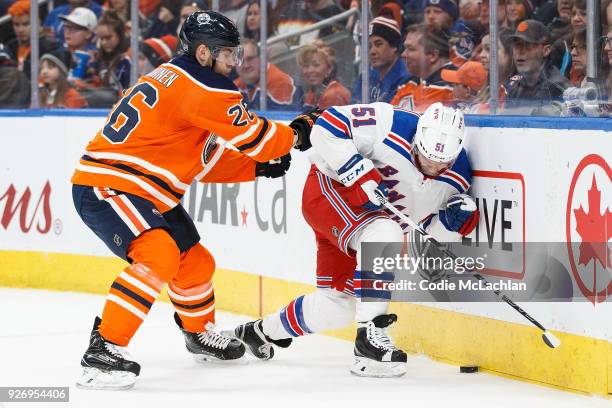 Iiro Pakarinen of the Edmonton Oilers shoves David Desharnais of the New York Rangers into the boards at Rogers Place on March 3, 2018 in Edmonton,...