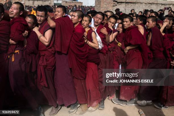 This picture taken on March 1, 2018 shows Tibetan Buddhist monks carrying a giant thangka for the unveiling ceremony during Monlam, otherwise known...