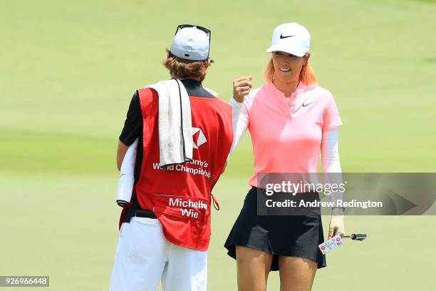 Michelle Wie of the United States celebrates with her caddie on the 18th green during the final round of the HSBC Women's World Championship at...