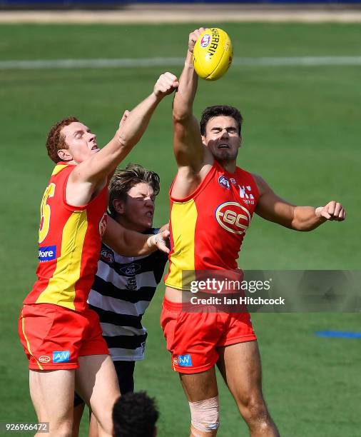 Jack Leslie and Rory Thompson of the Suns punch the ball away during the AFL JLT Community Series match between the Geelong Cats and the Gold Coast...