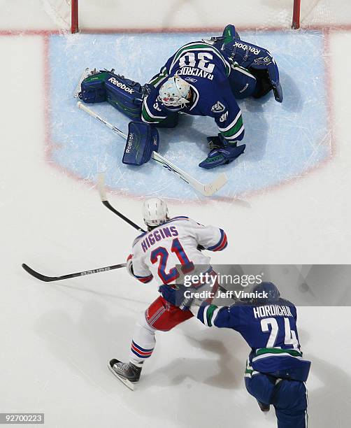 Andrew Raycroft of the Vancouver Canucks makes a save off the shot of Christopher Higgins of the New York Rangers as Darcy Hordichuk of the Canucks...