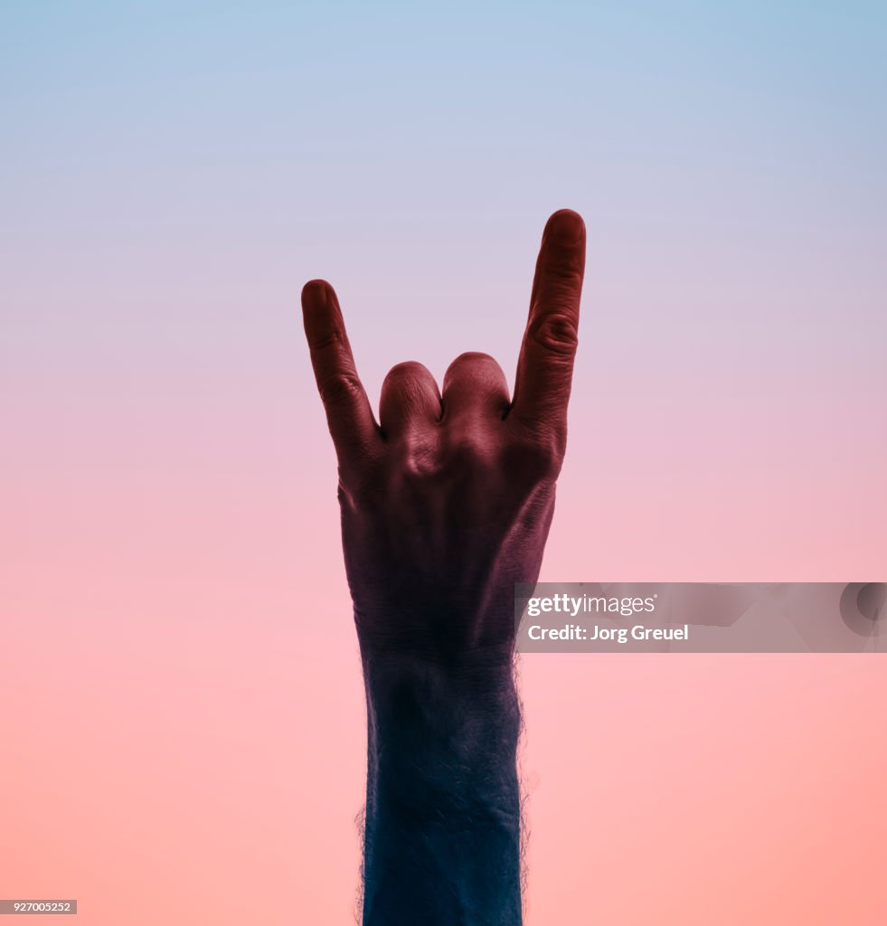 Male hand showing sign of the horns