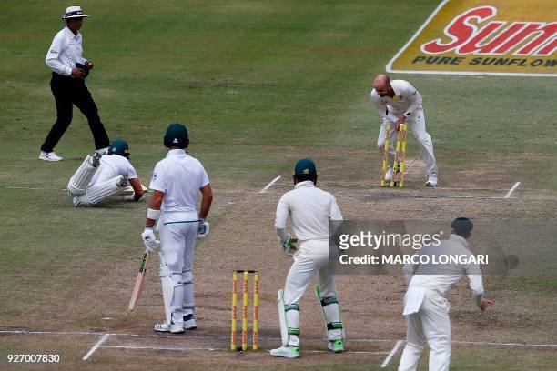 Australian bowler Nathan Lyon breaks the stumps to run out South African batsman AB de Villiers during the fourth day of the first Test cricket match...