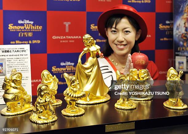 Model displays pure gold Disney character dolls showing Snow White and the seven dwarfs, priced at 30 million yen and produced by Tanaka Kikinzoku...