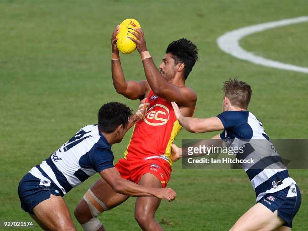 Aaron Hall of the Suns skips out of a tackle from Jordan Cunico and Jamaine Jones of the Cats during the AFL JLT Community Series match between the...