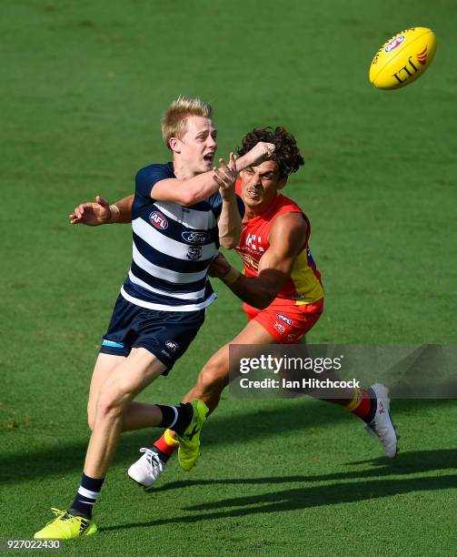 Zach Guthrie of the Cats handballs the ball away in front of Sean Lemmens of the Suns during the AFL JLT Community Series match between the Geelong...