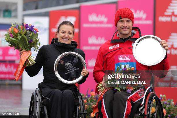 Switzerland's Manuela Schar poses with the winner's trophy after the elite women's wheelchair race half marathon alongside Switzerland's Marcel Hug...