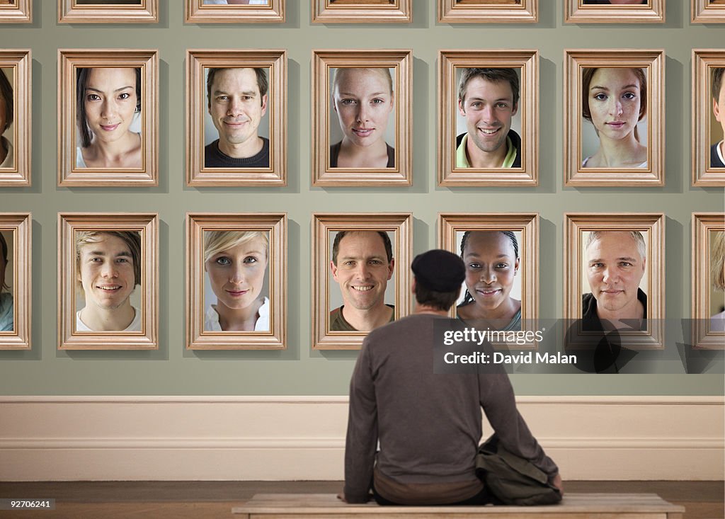 Man looking at wall of portraits in a gallery