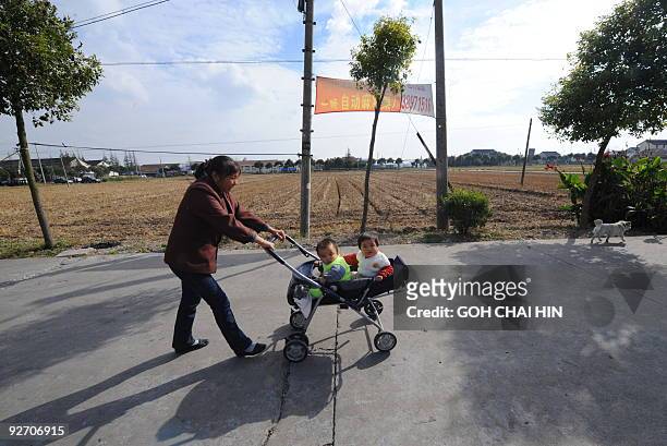Resident pushes a pram with her babies at Qigang village in Pudong district, a proposed site of the Disney park in Shanghai, on November 4, 2009....