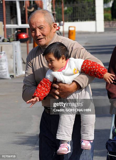 An elderly resident carries his grandchild at Qigang village in Pudong district, a proposed site of the Disney park in Shanghai, on November 4, 2009....