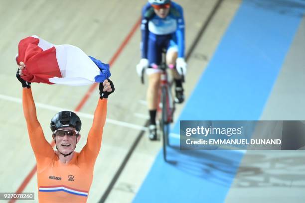 Hong Kong's Qianyo Yang cycles as Netherlands Kirsten Wild celebrates winning the women's points race final during the UCI Track Cycling World...