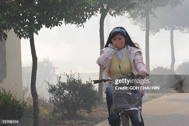Resident makes her way past a burning field after a burn off to produce nutrients, as farmers prepare for the next crop in the Qigang village in...