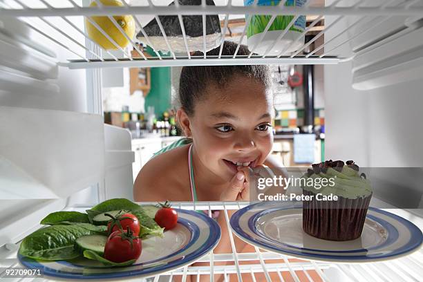 girl choosing between salad and cake - veleiding stockfoto's en -beelden