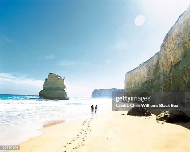 couple walking along a beach. - australian beach stockfoto's en -beelden