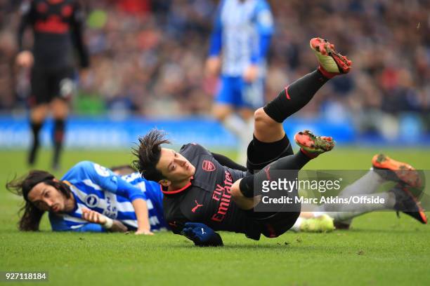 Mesut Ozil of Arsenal and Ezequiel Schelotto of Brighton and Hove Albion react after colliding during the Premier League match between Brighton and...