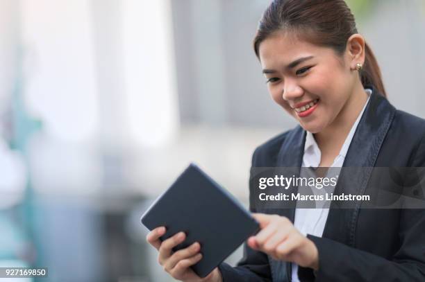 woman using a tablet outdoors - filipino woman smiling stock pictures, royalty-free photos & images