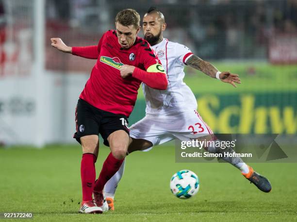 Nils Petersen of Freiburg is challenged by Arturo Vidal of Muenchen during the Bundesliga match between Sport-Club Freiburg and FC Bayern Muenchen at...