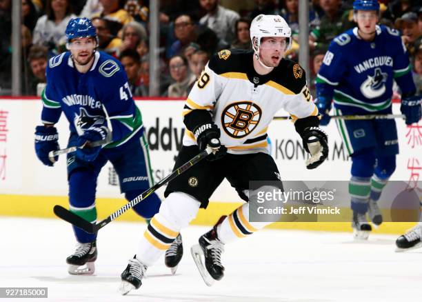 Sven Baertschi of the Vancouver Canucks and Tim Schaller of the Boston Bruins skate up ice during their NHL game at Rogers Arena February 17, 2018 in...