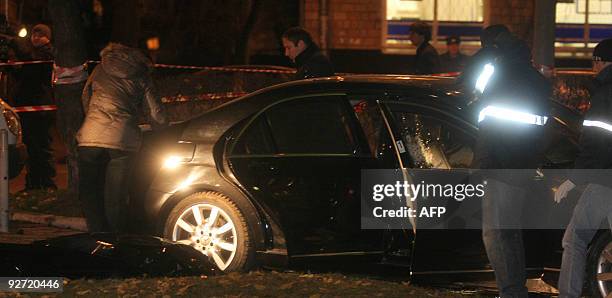 The body of slain Russian-Israeli businessman Shabtai von Kalmanovic lies in a black bag near his vehicle as forensic experts examine the crime scene...