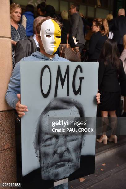 Protester holds a sign as Cardinal George Pell arrives at the Victorian Magistrates Court for an expected month-long committal hearing relating to...