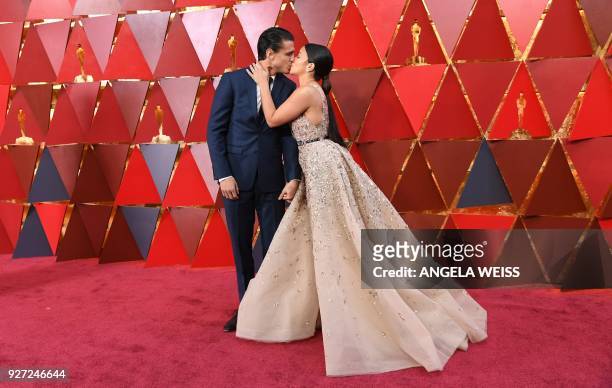 Actress Gina Rodriguez and her partner Joe Locicero kiss as they arrive for the 90th Annual Academy Awards on March 4 in Hollywood, California. / AFP...