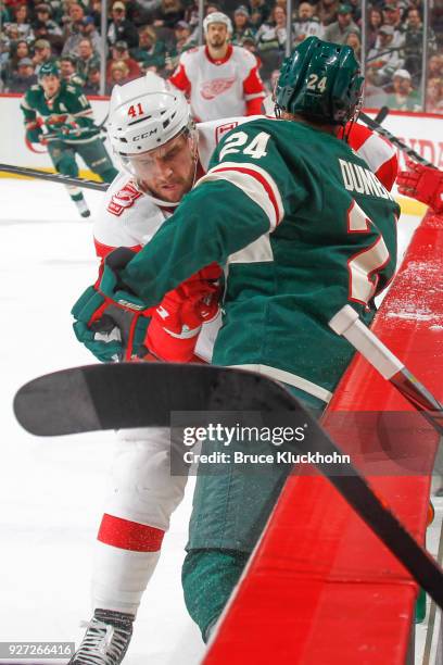 Matt Dumba of the Minnesota Wild and Luke Glendening of the Detroit Red Wings battle for the puck along the boards during the game at the Xcel Energy...