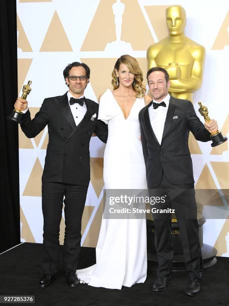 Actor Laura Dern poses with producers Dan Cogan and director Bryan Fogel , winners of the Best Documentary Feature award for 'Icarus,' in the press...