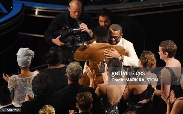 Director Jordan Peele is congratulated by British actor Daniel Kaluuya after he won the Oscar for Best Original Screenplay for "Get Out" during the...