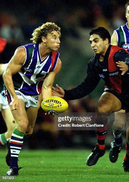 Shaun McManus of Fremantle has possession of the ball with Dean Rioli of Essendon in close pursuit, during the round 13, AFL match, between the...