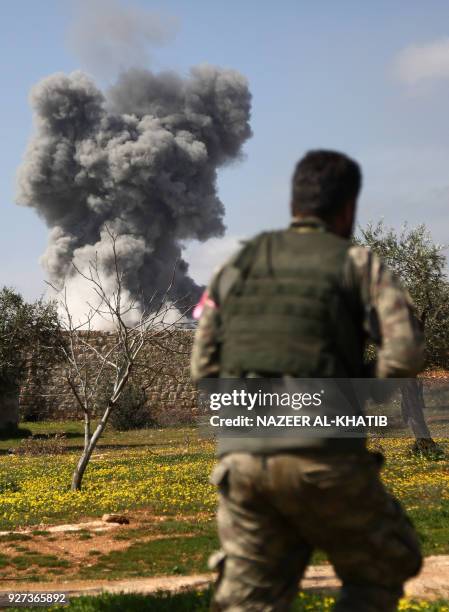 Turkish-backed Syrian opposition fighters are seen in the village of Jamanli, northeast of the Syrian city of Afrin, on March 3 as smoke billows in...