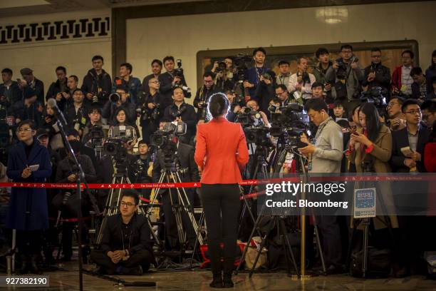 News reporter stands in front of members of the media inside the Great Hall of the People ahead of the opening of the first session of the 13th...