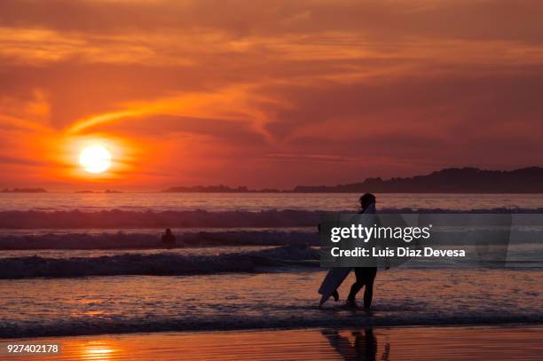 silhouette of surfers leaving the sea on the beach of la lanzada - pontevedra province ストックフォトと画像