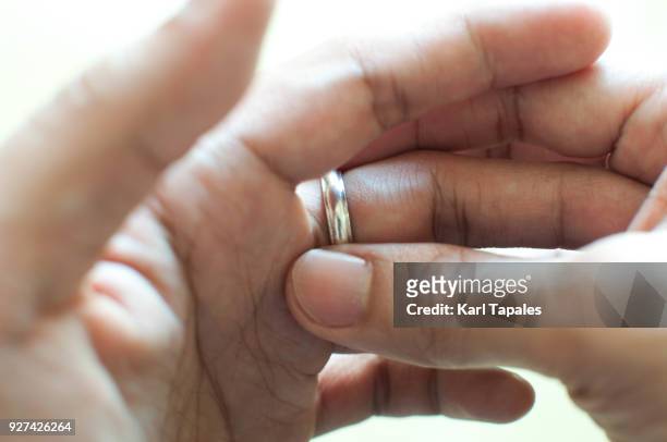 a man is holding his wedding ring - taking off wedding ring stock pictures, royalty-free photos & images