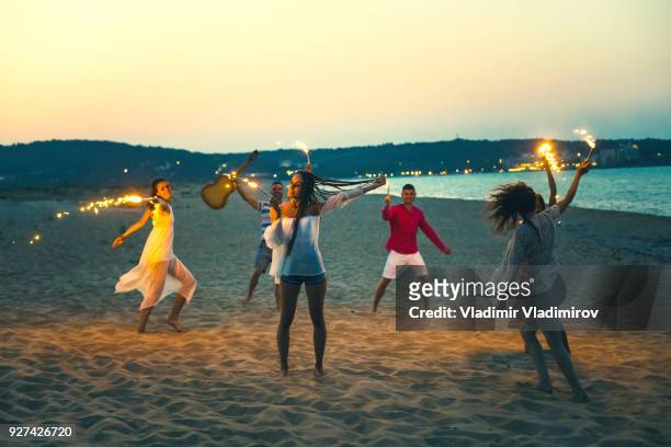 friends celebrating with fireworks on beach at night - bulgaria dance stock pictures, royalty-free photos & images