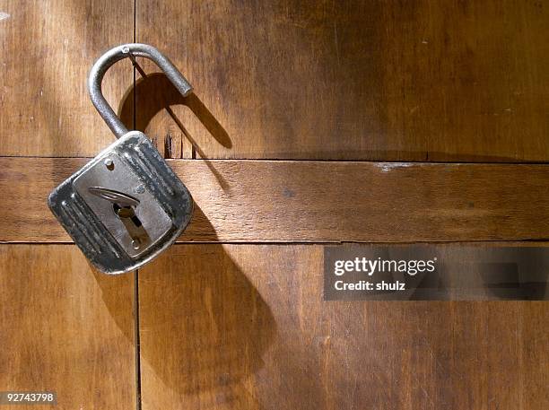 an antique padlock against a wood background - padlock stock pictures, royalty-free photos & images