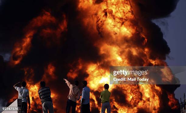 People watch the smoke and flames blowing from Indian Oil Corporation's fuel depot in Sitapura industrial area, which caught fire late Thursday...