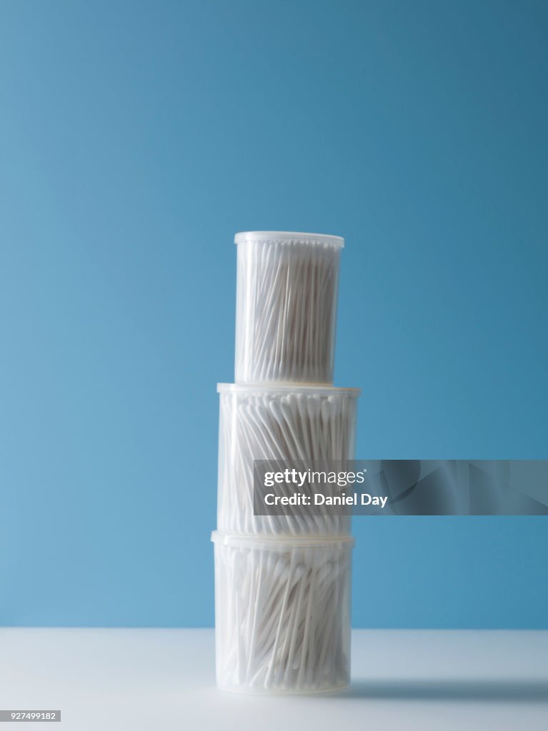 Pile of containers with earbud against a blue background