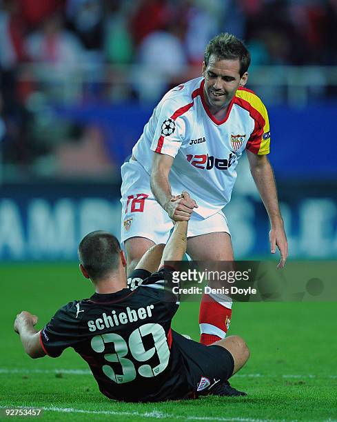 Fernando Navarro of Sevilla helps up Julian Schieber of VfB Stuttgart after the final whistle of the the UEFA Champions League Group G match between...