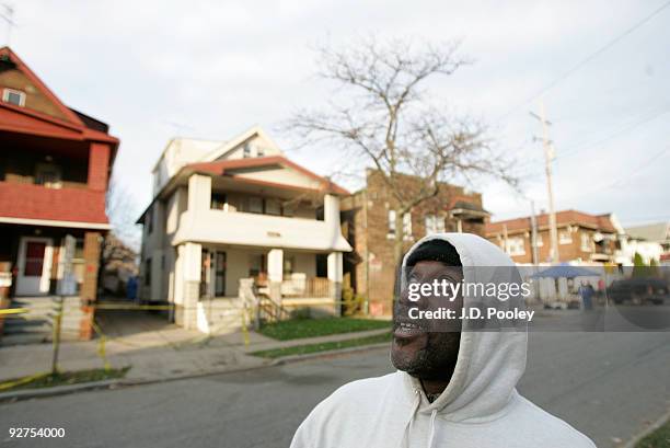 David Banks looks up at a news helicopter flying over, outside the home of Anthony Sowell November 4 in Cleveland, Ohio. Sowell has been in jail...