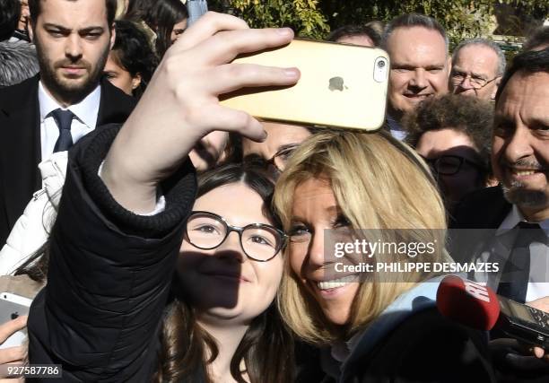 High school student takes a selfie photo with the French President's wife Brigitte Macron during a visit with the French Education Minister to...