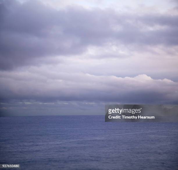 ultraviolet sky and clouds creating a matching colored ocean - timothy hearsum stock-fotos und bilder