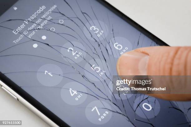Berlin, Germany A four digit security code is entered on an Apple Iphone with splintered glass on March 05, 2018 in Berlin, Germany.