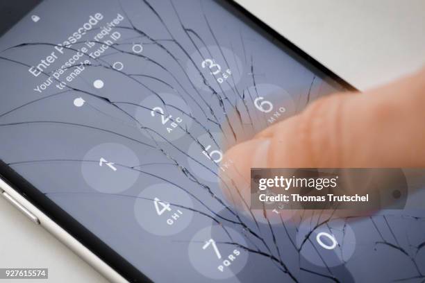 Berlin, Germany A four digit security code is entered on an Apple Iphone with splintered glass on March 05, 2018 in Berlin, Germany.