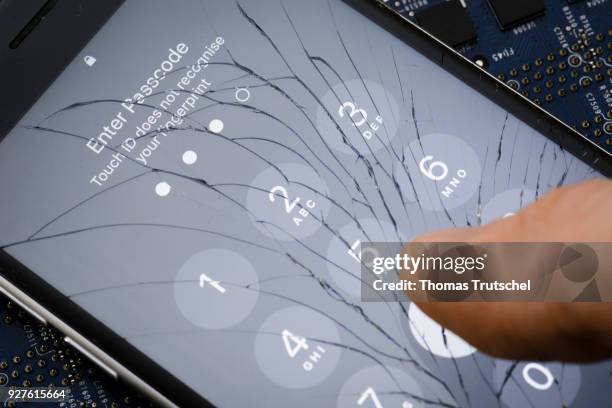 Berlin, Germany A four digit security code is entered on an Apple Iphone with splintered glass on March 05, 2018 in Berlin, Germany.