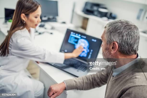 femme médecin montrant la scintigraphie cérébrale au patient - tomographie par émission de positrons photos et images de collection