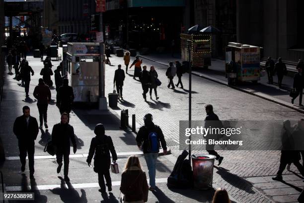 Pedestrians walk along Wall Street near the New York Stock Exchange in New York, U.S., on Monday, March 5, 2018. U.S. Stocks turned higher and...