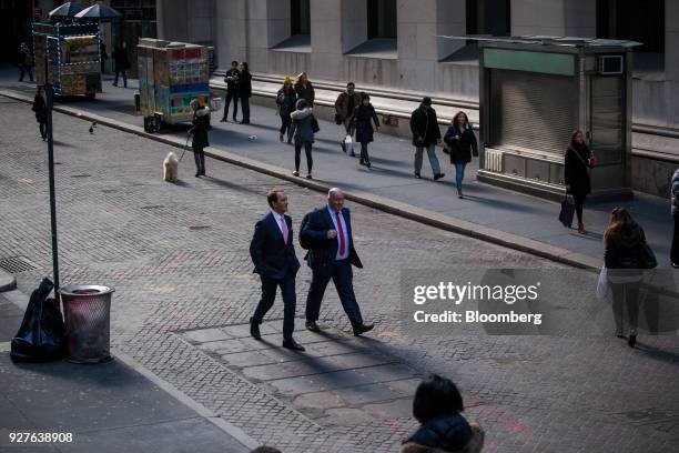 Pedestrians walk along Wall Street near the New York Stock Exchange in New York, U.S., on Monday, March 5, 2018. U.S. Stocks turned higher and...