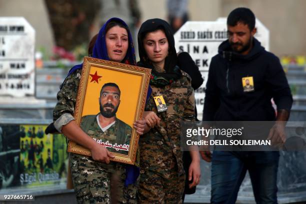 Mourners carry a portrait of a Kurdish fighter from the Syrian Democratic Forces who was killed in combat against Islamic State group in Deir Ezzor,...