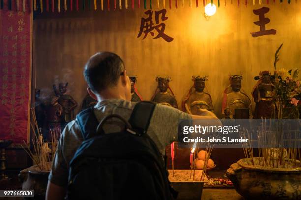 Lighting Joss Sticks at Man Mo Temple Hong Kong - Man Mo Temple or Man Mo Miu is a temple in Hong Kong that reveres both the God of Literature and...